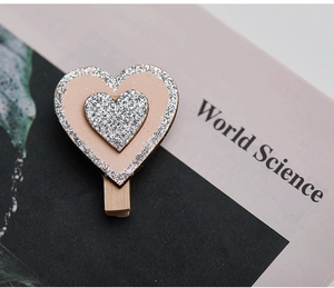 Macro shot of pink heart-shaped wooden peg with silver glitter detail for Christmas decor