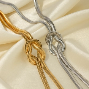Detail of 16k gold and silver knotted herringbone snake chains on beige silk