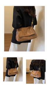 Detail view of brown vintage shoulder bag with gold metal buckle and chain strap
