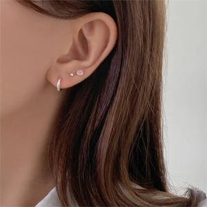 Close-up of 925 sterling silver hoop earrings with a pink smiley face enamel stud