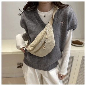 Action shot of beige corduroy crossbody bag with adjustable strap and multiple zippers