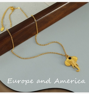 Close-up of golden elephant pendant necklace with black stone eye and fine chain link