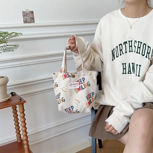 Detail of beige corduroy mini tote bag with colorful Keep Smiling text and snap button