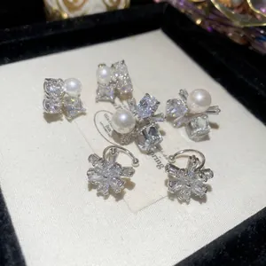 Elegant zircon flower and pearl ear cuffs with silver base on a textured display card