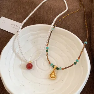Ethnic gourd necklace with tiger eye stone and pearls on white ceramic plate