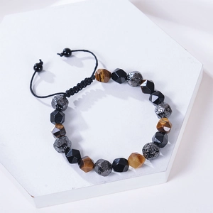 Tiger eye and obsidian beaded bracelet with adjustable black braided cord on white podium