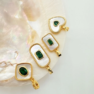 Close-up of vintage 18K gold plated shell pendants with green gemstones on a shell