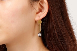 Detail of long gold titanium earrings with white pearls shown on a model's ear
