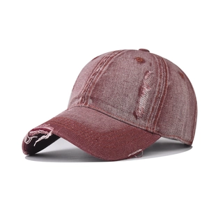 Close-up of distressed vintage denim baseball cap showing torn details and washed red texture