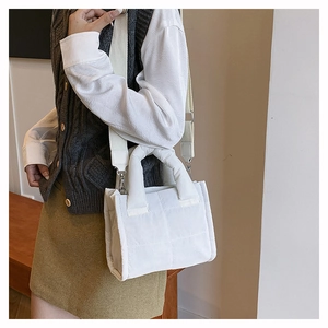 Quilted white crossbody bag with detachable wide strap worn by a female model
