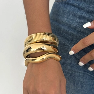 Dreiteiliges 18K vergoldetes Edelstahl-Armreif-Set, getragen von einem Model vor Denim