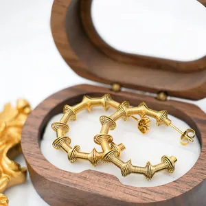 Detail of creative gold spiral hoop earrings with studs in a dark wood jewelry box