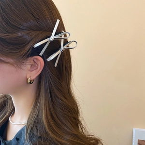 Detail of silver metallic leather bow hair clips with long ribbons on brunette hair