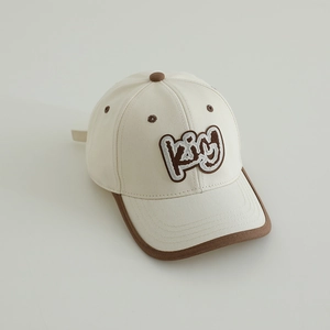 Detail of minimalist cream baseball cap with brown trim and 3D King letter embroidery