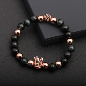 Detail of rose gold crown charm with black zircons on blue tiger eye beaded bracelet