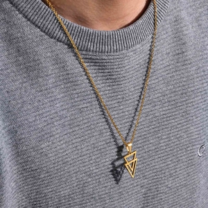 Close-up of gold geometric double triangle pendant necklace worn on a grey sweater