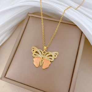 Close-up of gold butterfly necklace pendant with pink glitter wings and clear rhinestones