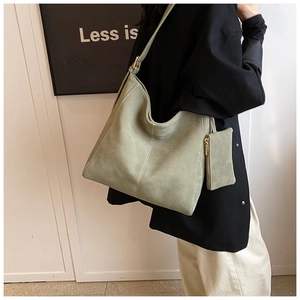 Detail of sage green hobo shoulder bag with contrast stitching and matching small pouch