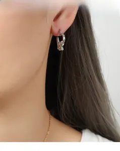 Close-up of minimalist silver bow earrings and gold necklace on model with soft lighting