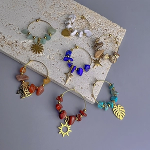 Detail of bohemian gold hoop earrings with natural gravel stones and charms