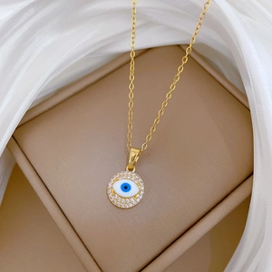 Detail of gold evil eye necklace featuring sparkling crystals on a silk backdrop
