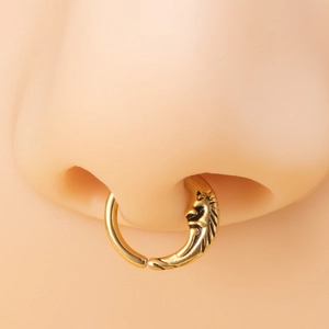 Close-up of a gold nose ring with a black embossed face charm on a realistic model