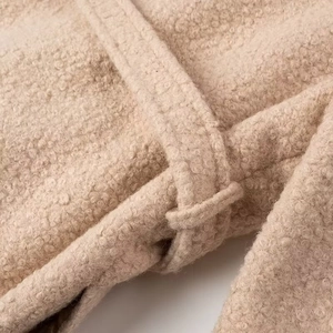 Close-up of beige fleece coat fabric texture and metallic waist belt buckle detail
