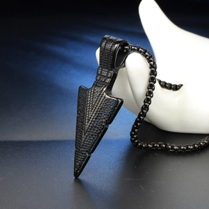 Detailed macro view of black textured arrow pendant necklace on professional model hand