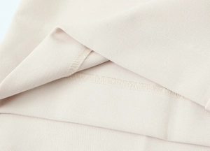 Dettaglio del tessuto beige e cuciture professionali sulla giacca corta stile blazer
