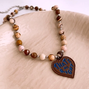 Close-up of vintage beaded necklace with marble beads and engraved brown heart pendant