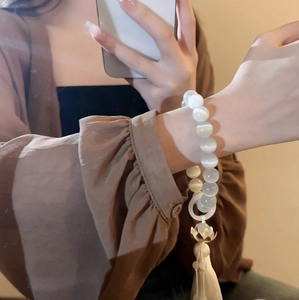 Detailed view of opal cat-eye lotus bracelet with beaded chain and long white tassel