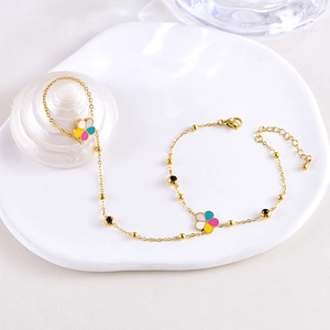 Golden hand chain ring with colorful clover flowers and butterfly on a white ceramic plate