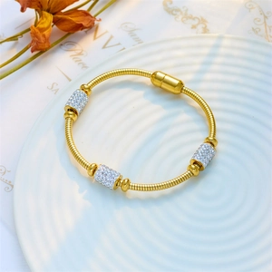 Gold snake chain bracelet with sparkling crystal sliders and magnetic clasp on a tray