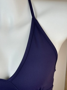 Detailed close-up of dark purple halter neck strap and fine stitching on the athletic top