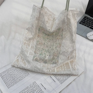 Détail du sac cabas en dentelle blanche avec broderie florale et anse en corde verte