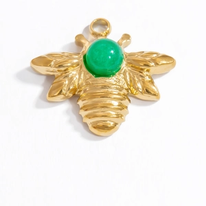Close-up of golden bee pendant with a green gemstone inlay on a white background