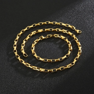 Detail of gold and black checkered box chain necklace and bracelet on dark background