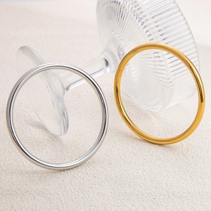 Polished minimalist stainless steel bangles in gold and silver finishes on glass