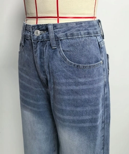 Detail of high-waisted blue washed jeans showing precision stitching and button craft