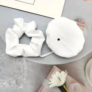 Close-up of white fabric drink cover scrunchie set with elastic hole on a grey tray