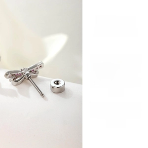 Macro detail of silver dragonfly stud earring featuring pink cubic zirconia and screw back