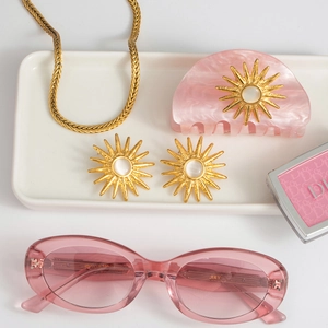 Flat lay of pink marble sunburst earrings, matching hair clip and gold flat chain necklace