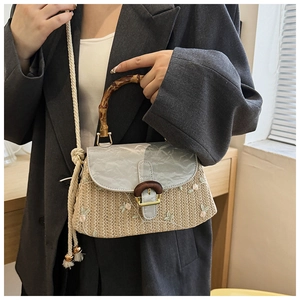 Detail of straw woven bag with bamboo handle and elegant floral embroidery details
