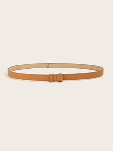 Detail of a slim brown Saffiano leather waist belt featuring a minimalist metal buckle