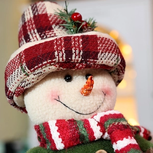 Christmas snowman doll with plaid hat and red scarf in warm holiday bokeh background