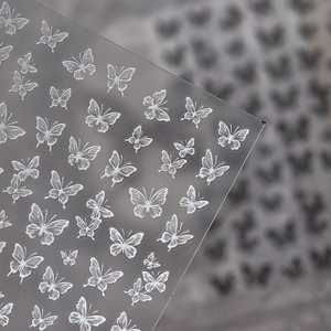 Dettaglio macro di adesivi per unghie con farfalle bianche 3D e trame in rilievo