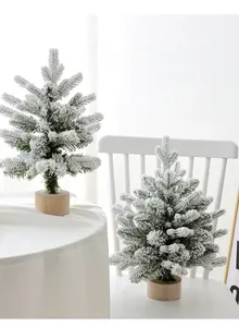 Detail of two mini flocked Christmas trees with snow effect on natural wood bases