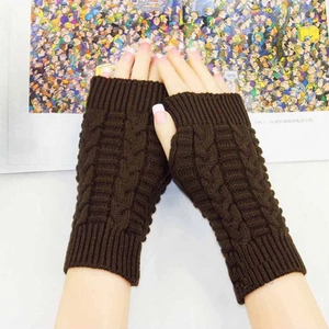 Close-up of dark brown cable-knit fingerless gloves with ribbed edges on a book