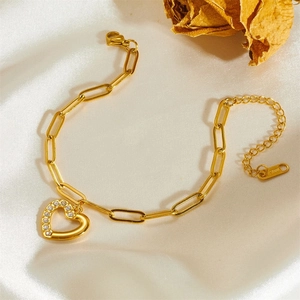 Gold paperclip chain heart bracelet with pavé crystals on white silk background