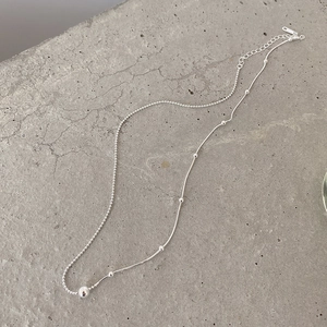 Macro shot of silver dual-layer snake and bead chain with polished ball pendant detail